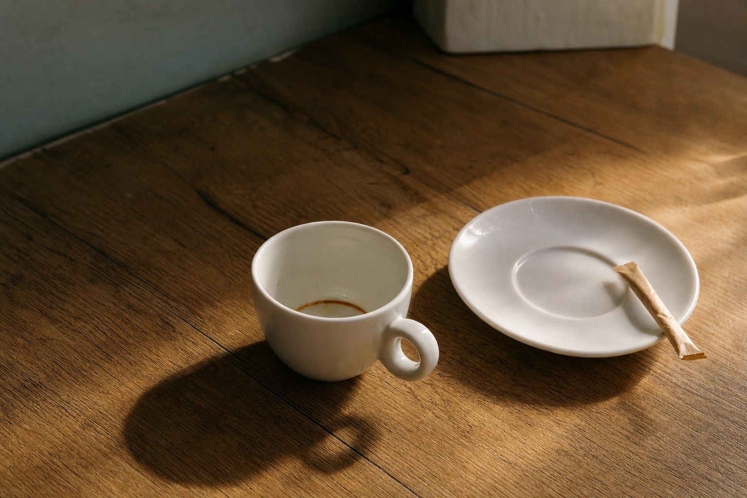 La tazzina vuota Una tazzina di caffè vuota sul tavolo di legno, con il piattino accanto